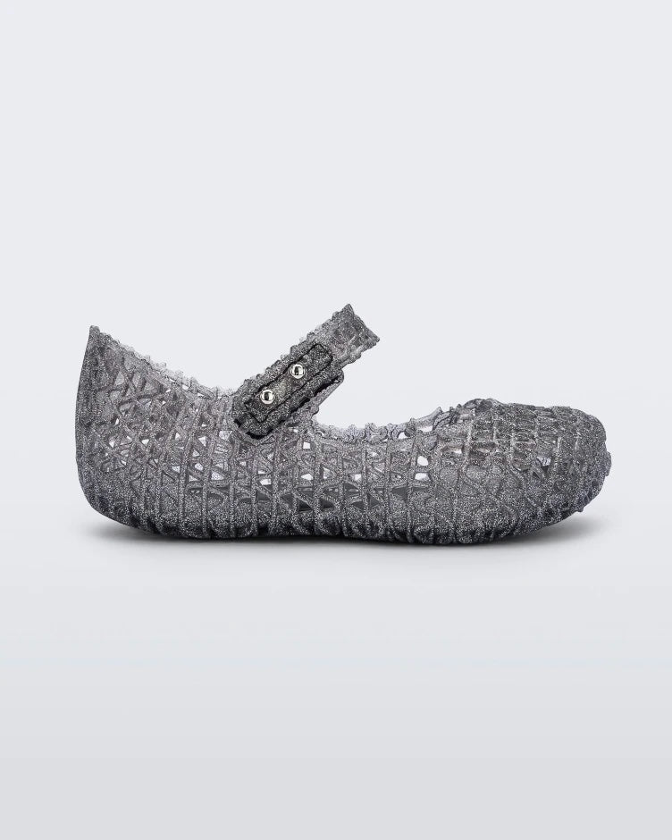 Side view of a black glitter Mini Melissa Campana flat with a snap strap for baby and an open woven texture, leaning on eachother.
