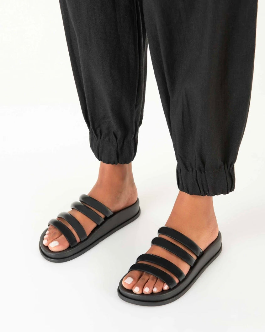 A model's legs wearing black pants and a pair of Black Melissa Soft Wave Slides with 4 front straps.