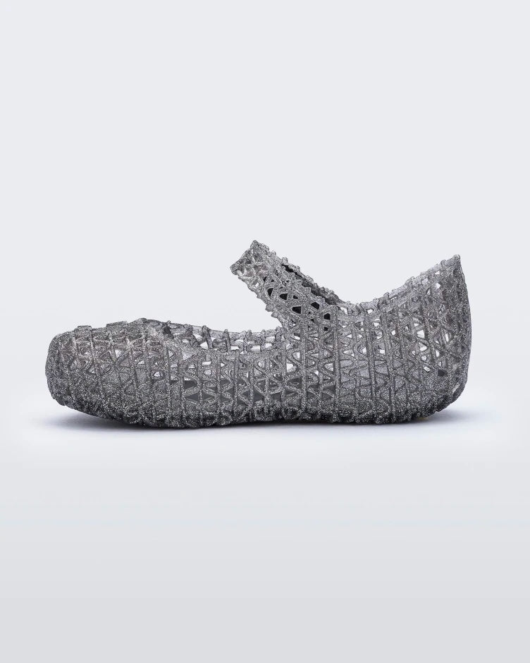 An inner side view of a black glitter Mini Melissa Campana flat with a snap strap for baby and an open woven texture.