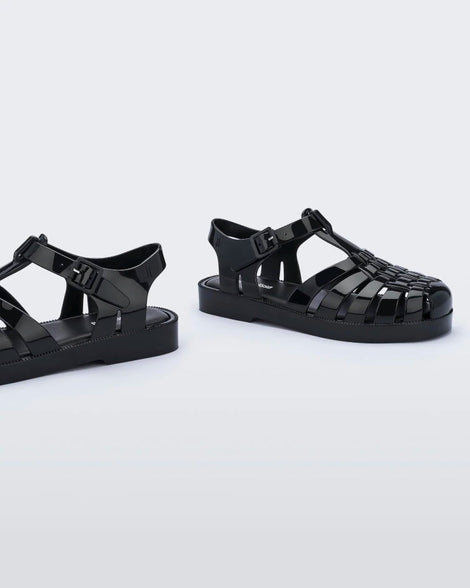 A side view of a pair of black Mini Melissa Possession sandals with several straps and a black base.