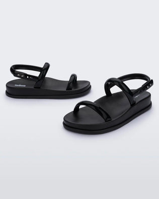An angled front and side view of a pair of black Melissa Soft Wave Sandals with a front and ankle strap.