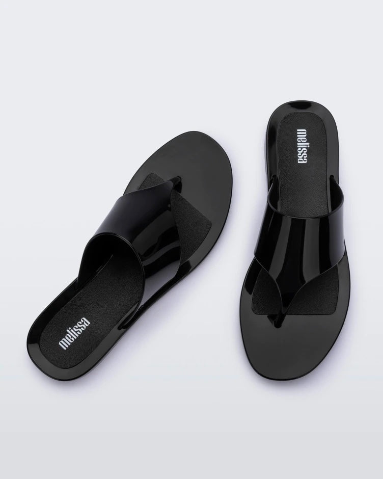 A top view of a pair of black Melissa Essential Chic Flip Flops with a wide upper strap.