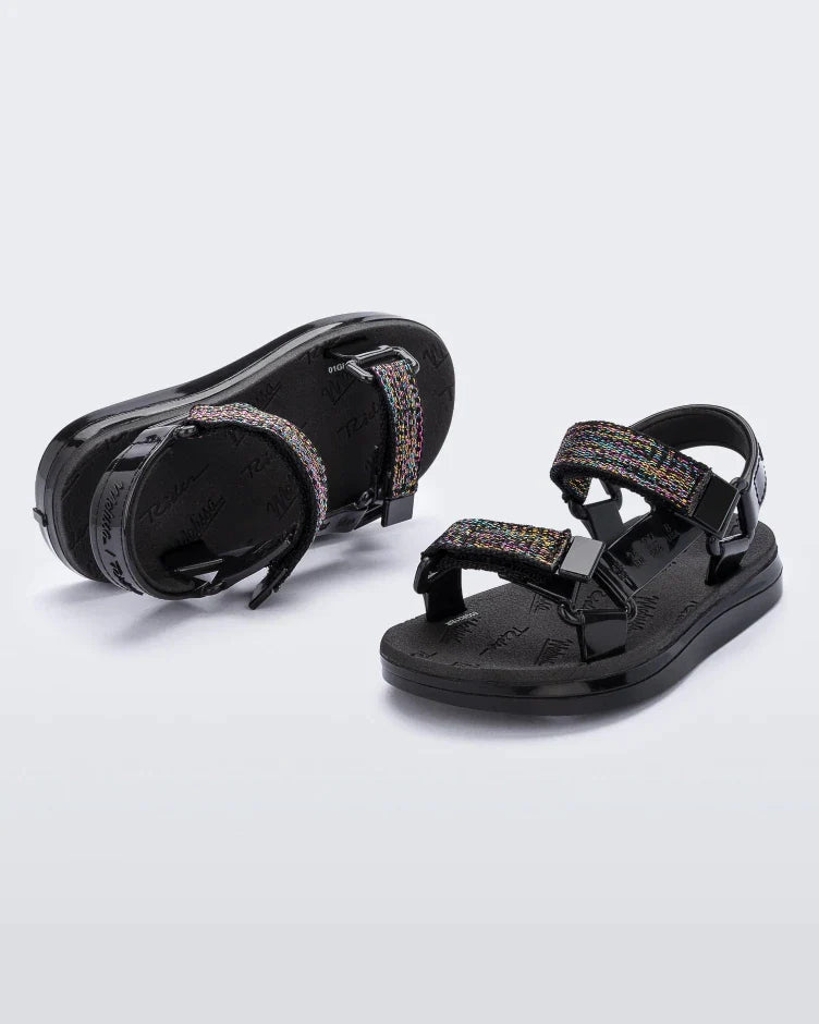 Angled view of a pair of black Mini Melissa Papete sandals with black glitter straps.