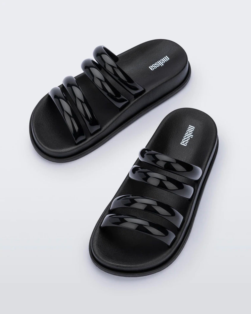 An angled top view of a pair of Black Melissa Soft Wave Slides with 4 front straps.