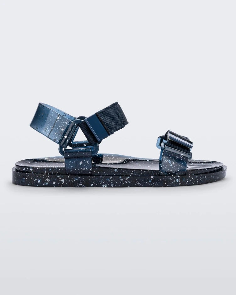 Side view of a blue/silver glitter Melissa Wide Papete sandal with velcro ankle and front straps.