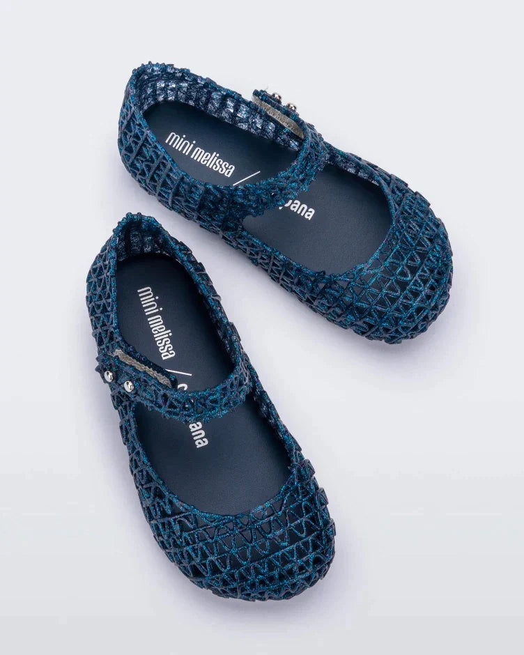 A top view of a pair of blue glitter Mini Melissa Campana flats with a snap strap for baby and an open woven texture.