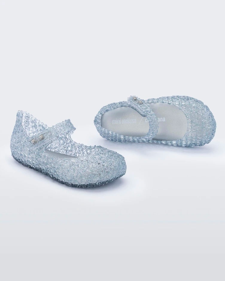 Top and angled view of a pair of Mini Melissa Campana flats for baby in clear with an open woven texture.