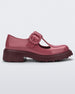 Side view of a Burgundy Mini Melissa Jackie loafer with a Burgundy base, two cut outs, a Burgundy buckle detail strap and brown sole.