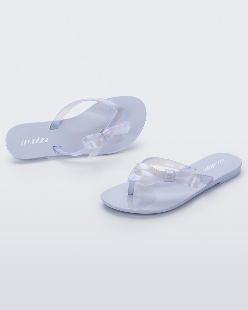 An angled front and side view of a pair of Lilac/Blue Pearl Mini Melissa Harmonic Sweet flip flops.