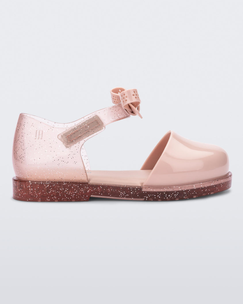 Side view of a pink Mini Melissa Amy sandal with a pink closed toe section and a back pink glitter strap with a lace like bow detail.
