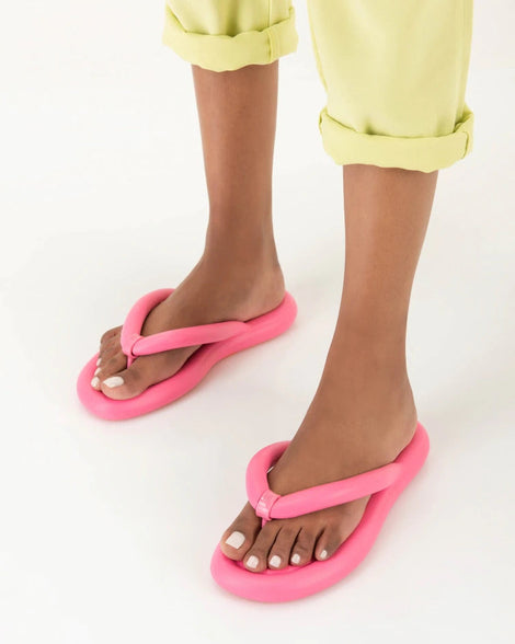 A model's legs wearing a pair of pink Melissa Free Flip Flops with puffer-like straps.