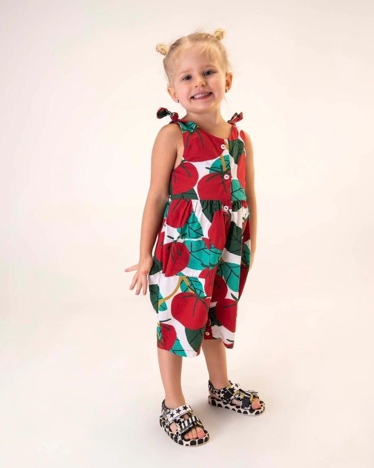 A young model posing for a picture in a patterned dress and a pair of beige/black Mini Melissa Ping Pong sandals with a black and white patterned base, sole and velcro straps.