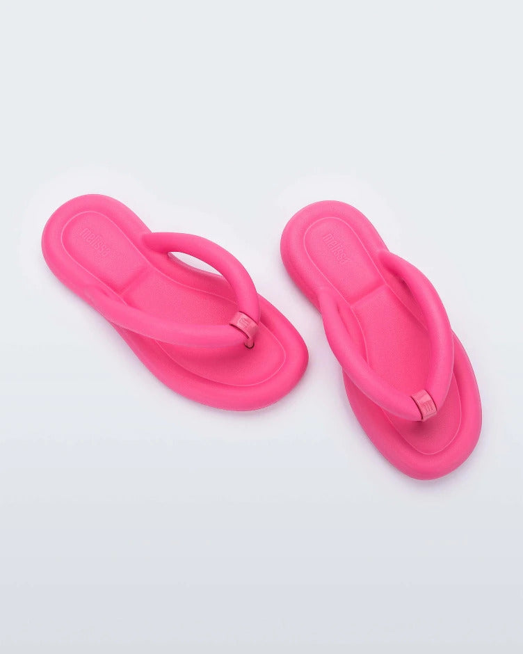 Top view of a pair of pink Melissa Free Flip Flops with puffer-like straps.