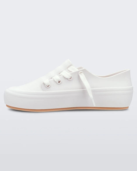 An inner side view of a white/beige Melissa Ulitsa sneaker with a white base, laces and a beige sole.