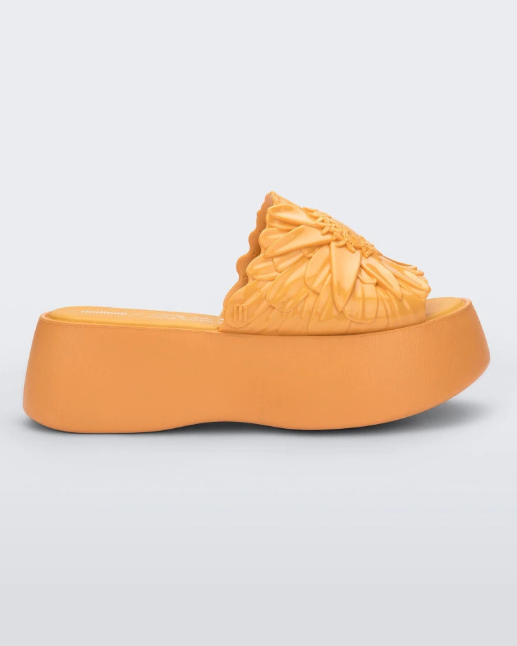 Side view of a yellow Melissa Panc Becky platform slide with a flower on top.