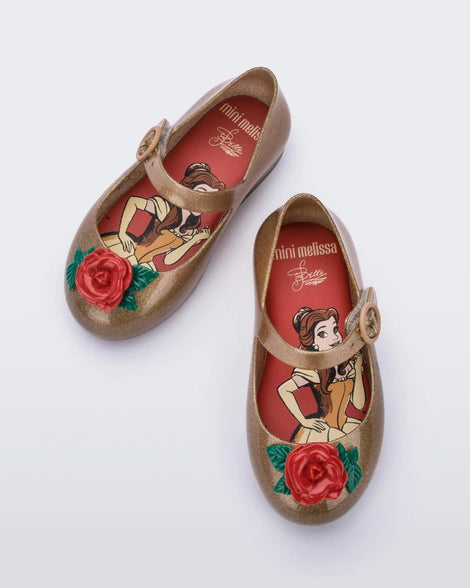 Top view of a pair of gold/red Mini Melissa Sweet Love Princess flats with a gold base with Belle in script on the side, a top strap, a rose detail on the toe and a drawing of Belle of Beauty and the Beast on the insole.