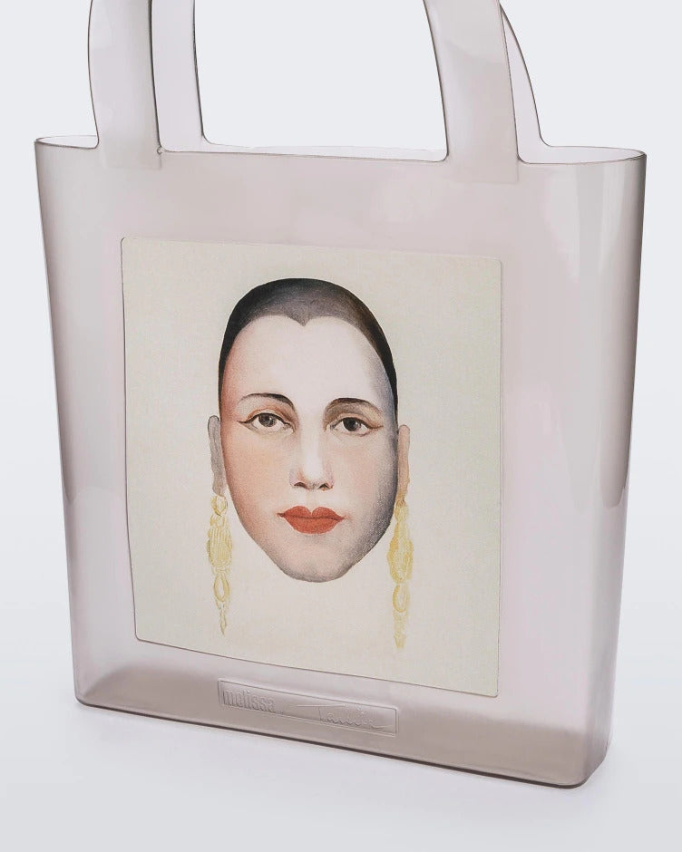 An Adult Melissa Canvas + Tarsila Do Amaral Bag with a picture of a woman's face on it.