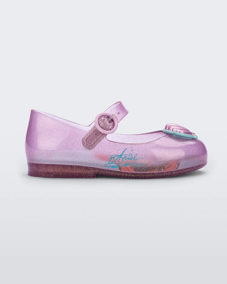 Side view of a pink Mini Melissa Sweet Love Princess flat, with a pink base, a top strap, Ariel in script on the side, a shell detail on the toe, and a drawing of Ariel of The Little Mermaid on the insole.