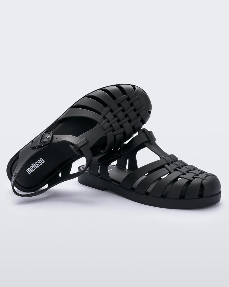 Top and anglef view of a pair of Melissa Possession fisherman sandals in black with a matte finish, cut out fishermen strap detail and buckle closure