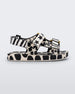 Side view of a beige/black Mini Melissa Ping Pong sandal with a black and white patterned base, sole and velcro straps.
