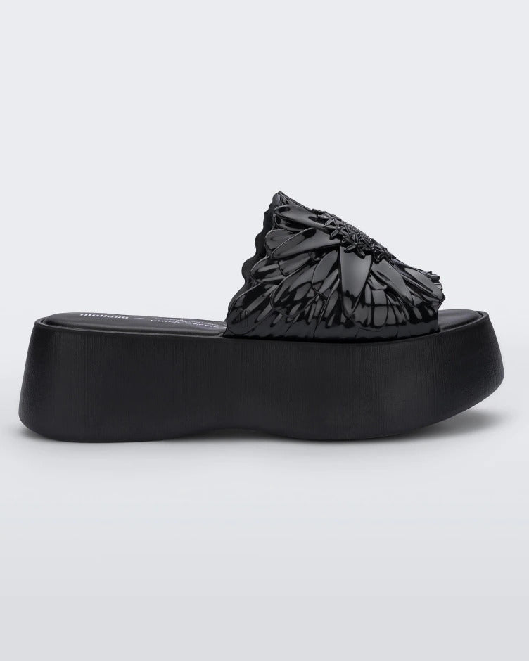 Side view of a black Melissa Panc Becky platform slide with a flower on top.