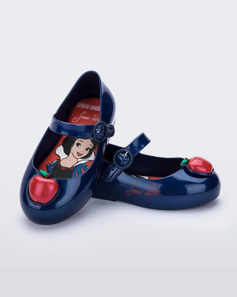 An angled top and side view of a pair of Metallic Blue/Red Mini Melissa Sweet Love Princess flats with a metallic blue base, a top strap, Snow White in script on the side, an apple detail on the toe, and a drawing of Snow White on the sole.