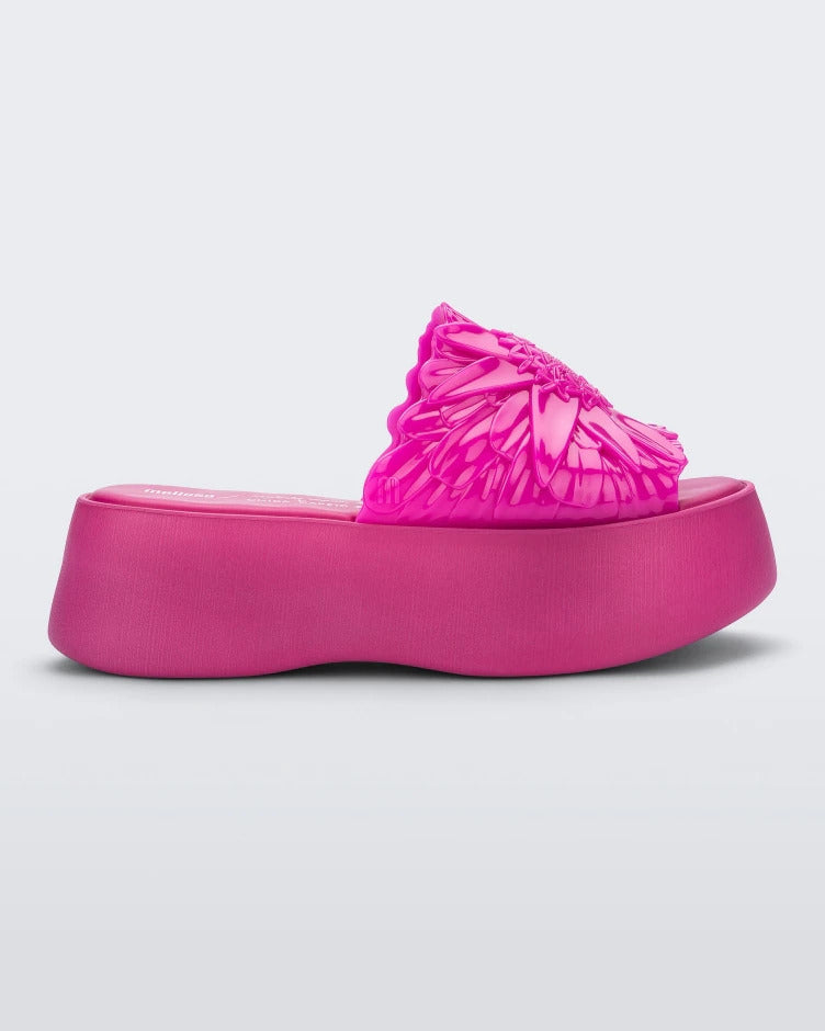 Side view of a pink Melissa Panc Becky platform slide with a flower on top.
