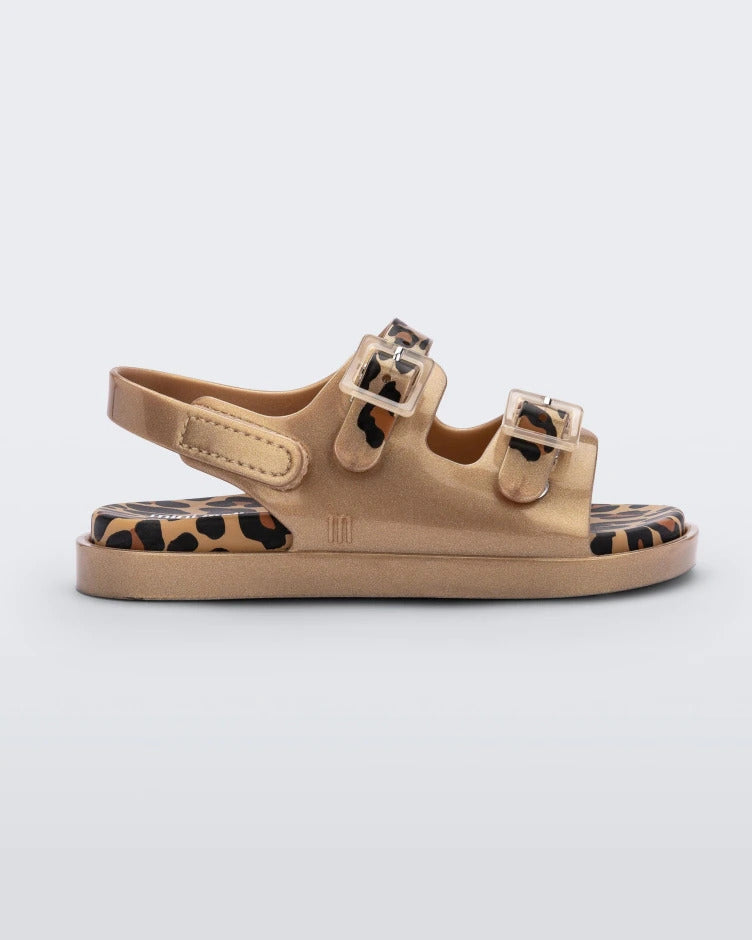 Side view of a gold/brown Mini Melissa Wide Sandal with a gold base, cheetah print insole, cheetah print straps and two buckles on top.