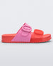 Side view of a Red/Pink Melissa Cozy slide with two red and pink straps with a buckle detail.