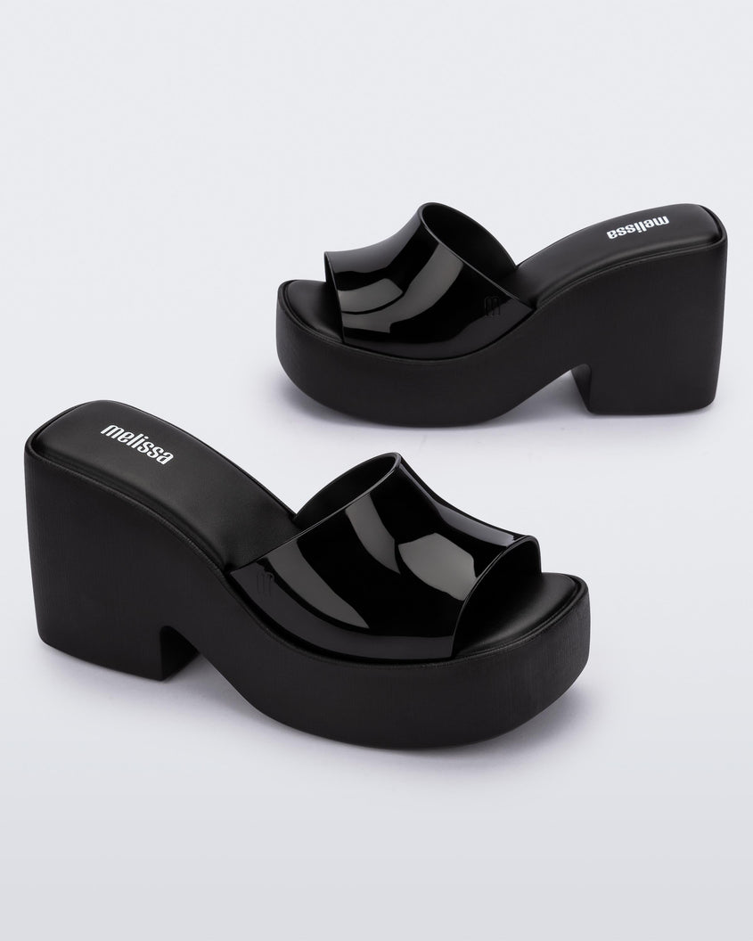 Angled view of a pair of Melissa Posh platform slides in Black