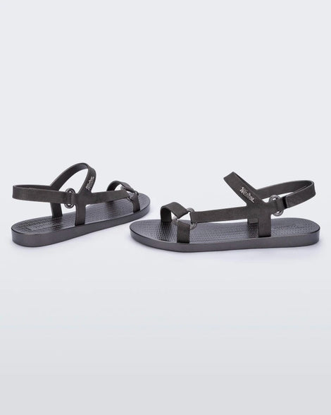 An angled side view of a pair of graphite metallic Melissa Sun Downtown sandals with a front and ankle strap joined together by a vertical strap and a triangle buckle.