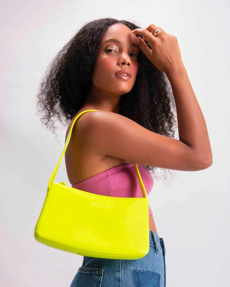 A model posing with a neon green Melissa Baguete handback on her shoulder.
