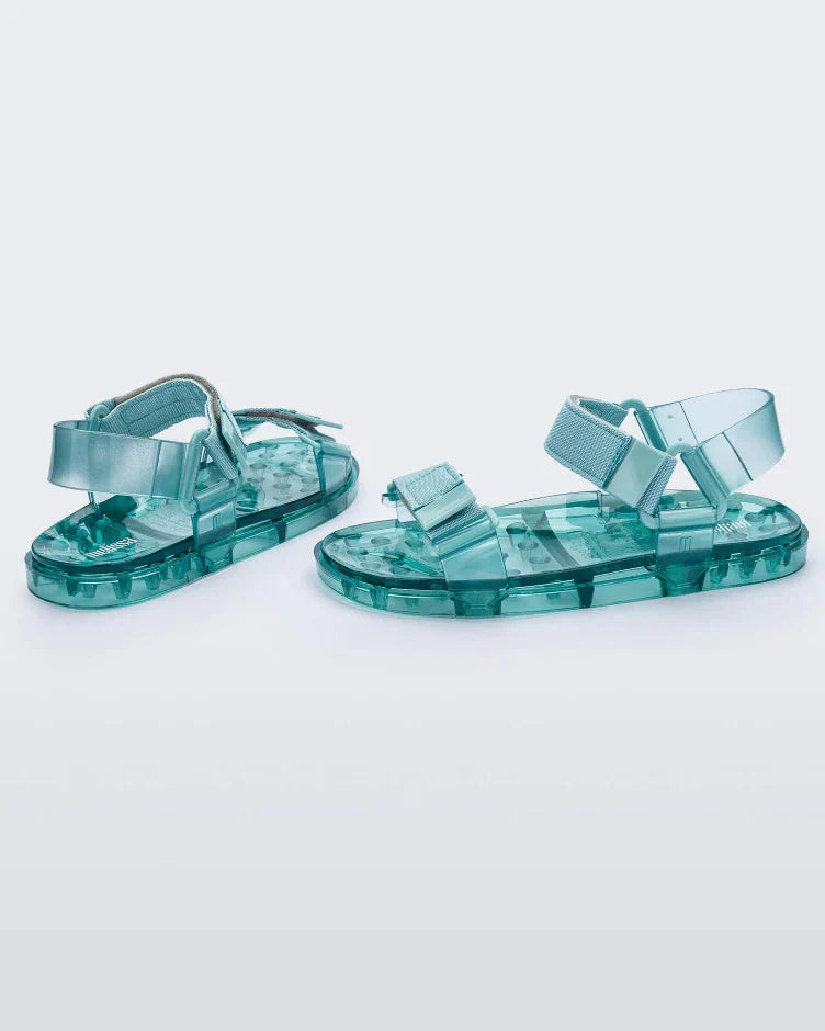 Angled view of a pair of Melissa Wide Papete sandals with transparent green sole and green velcro straps