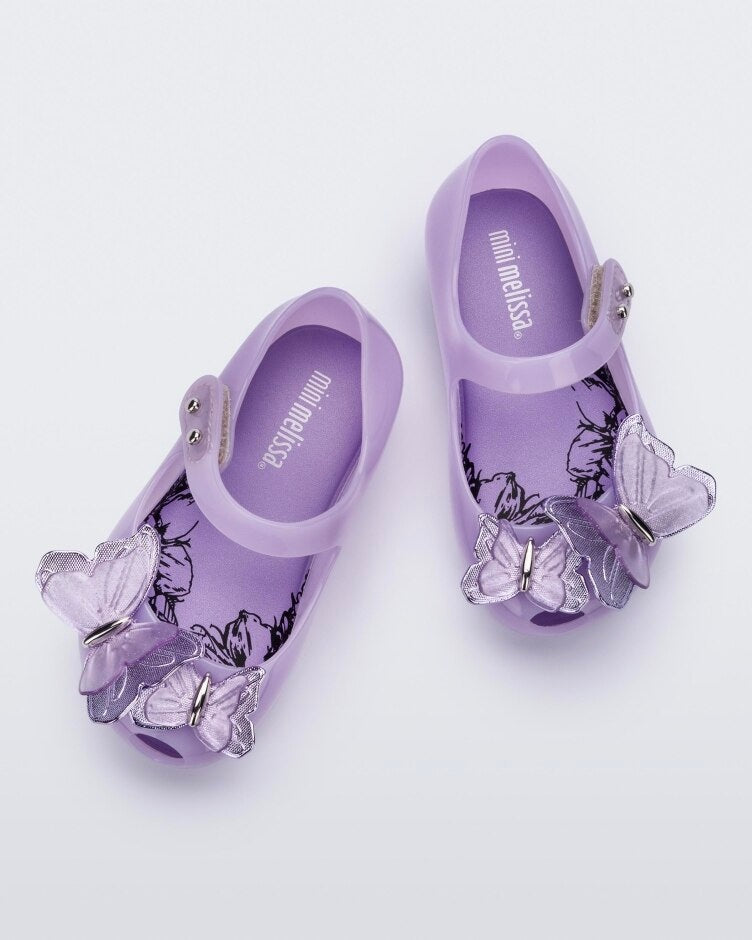 Top view of a pair of lilac Mini Melissa Ultragirl Butterfly flats with a top strap and two butterfly details on the toe.
