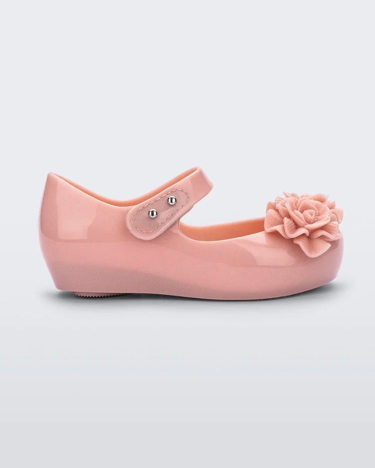 Side view of a light pink Mini Melissa Ultragirl Garden flat with a top strap and two rose details on the toe.