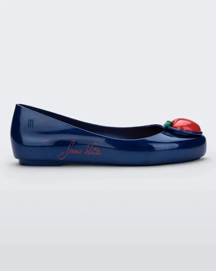 Side view of a blue Mini Melissa Sweet Love Princess flat, with a blue base, Snow White in script on the side, an apple detail on the toe, and a drawing of Snow White on the sole.