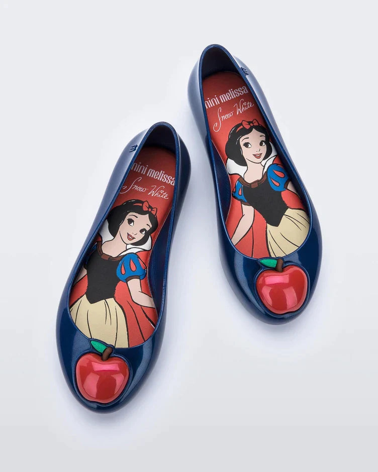 Top view of a pair of blue Mini Melissa Sweet Love Princess flats, with a blue base, Snow White in script on the side, an apple detail on the toe, and a drawing of Snow White on the sole.