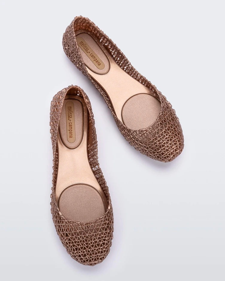 Top view of a pair of Melissa Campana flats in gold with an open woven texture.