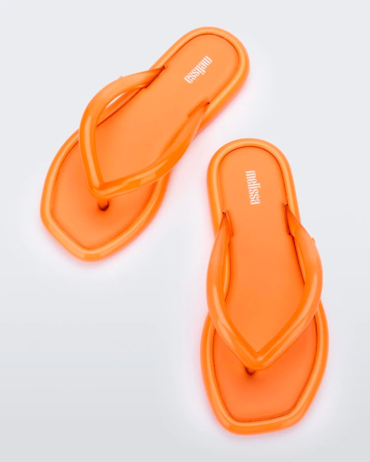 Top view of a pair of orange Melissa Airbubble Flip Flops.