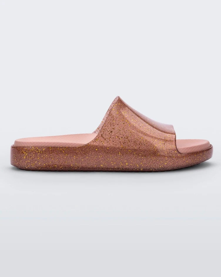 Side view of a pink glitter Mini Melissa Cloud slide with a solid light pink insole and a glitter pink base.