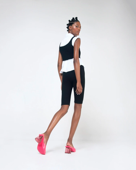 Model in black shorts wearing a pair of pink Candy heels