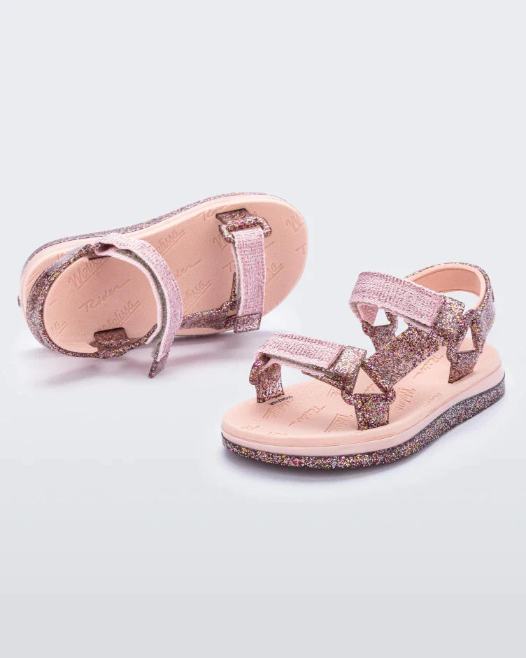 Angled view of a pair of pink and glitter Mini Melissa Papete sandals.