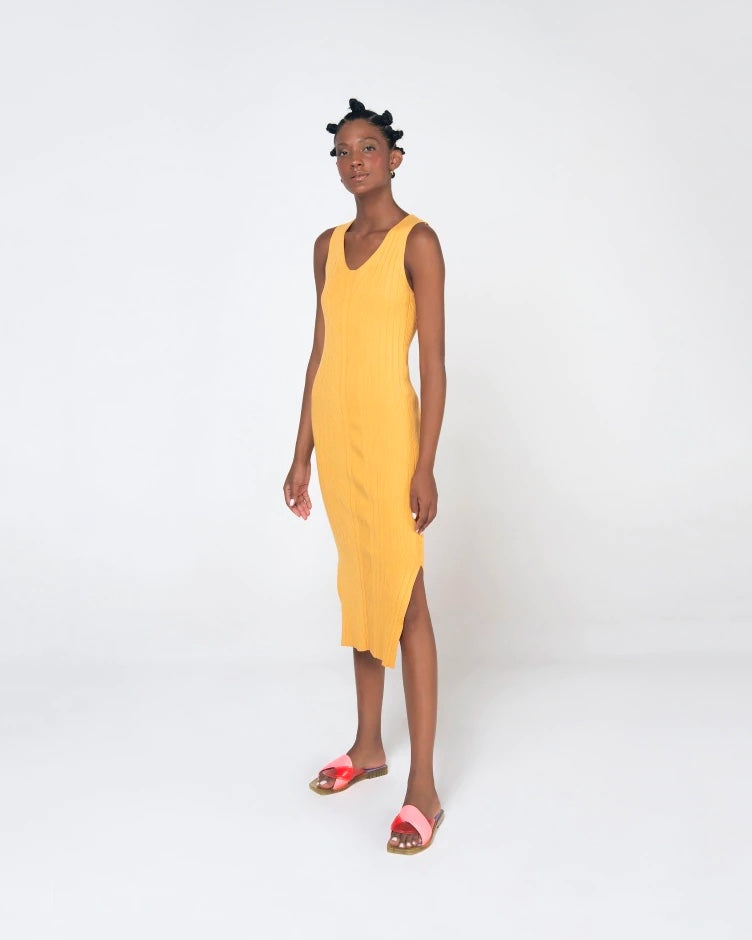 A model posing for a picture in a yellow dress and a pair of pink/green/lilac Melissa Brigitte slides with a pink weft designed upper strap.