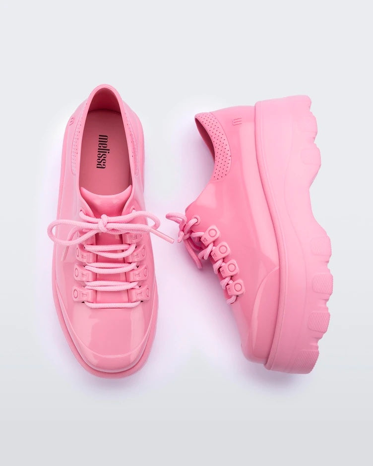 A top and side view of a pair of solid pink platform Melissa Kick Off Sneakers with laces.
