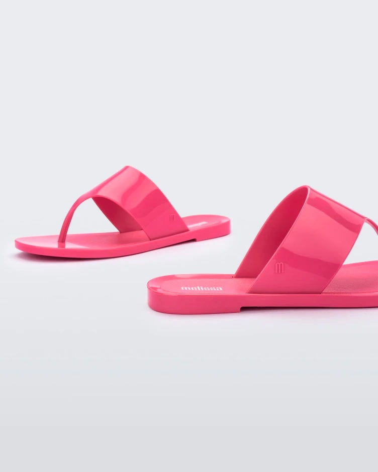Side view of a pair of pink Melissa Essential Chic Flip Flops with a wide upper strap.