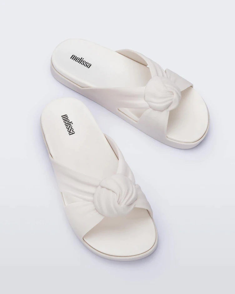 Top view of a pair of white Melissa Plush slides with a twist front strap detail.