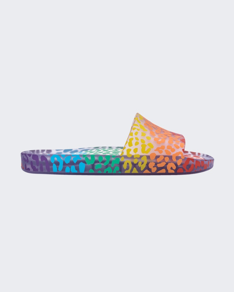 An outter side view of a clear / orange Melissa Rainbow Beach slide with a clear base and a rainbow cheetah print pattern.