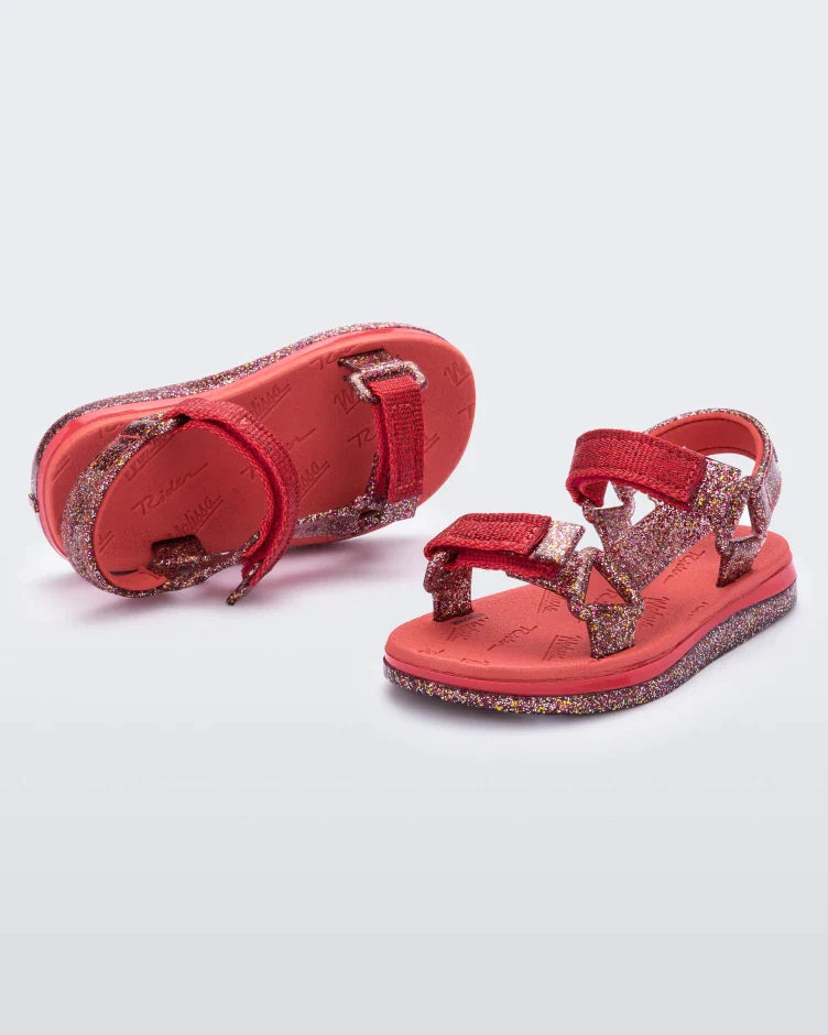 Top and angled view of a pair of red and glitter Mini Melissa Papete sandals.