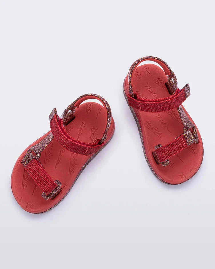 Top view of a pair of red and glitter Mini Melissa Papete sandals.
