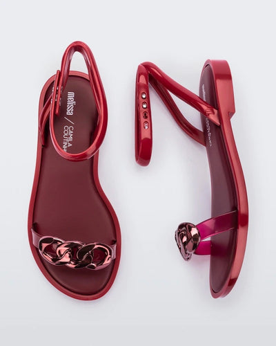 A top and side view of a pair of red Melissa Dare sandals with a red metal chain buckle.